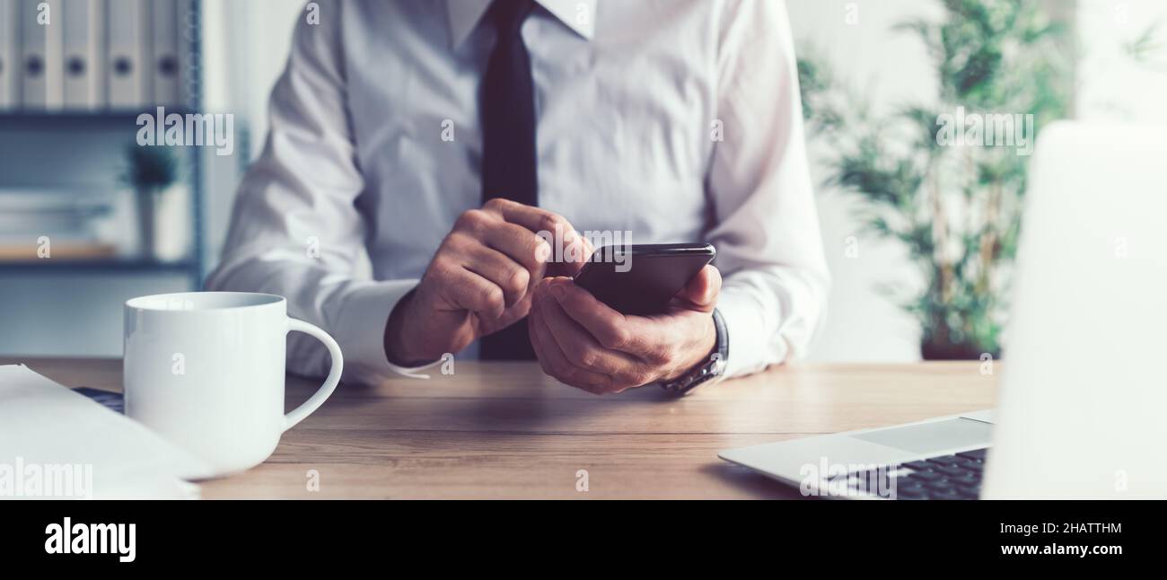 Concetto di comunicazione aziendale, uomo d'affari che utilizza lo smartphone mobile in ufficio per inviare messaggi di testo, fuoco selettivo Foto Stock