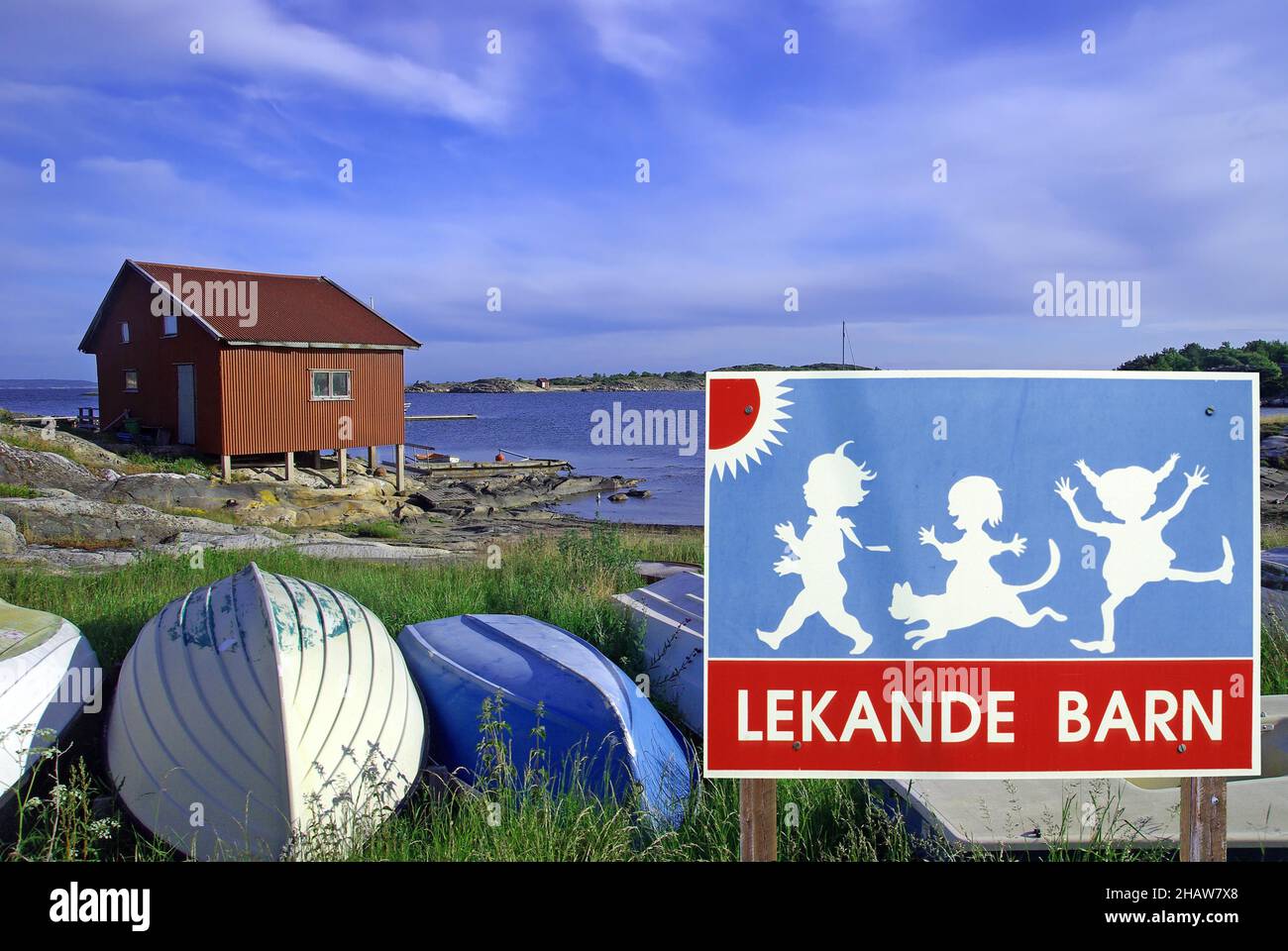 Bambini che giocano sul cartello stradale, barche in paesaggio calmo, composizione, Svezia Foto Stock