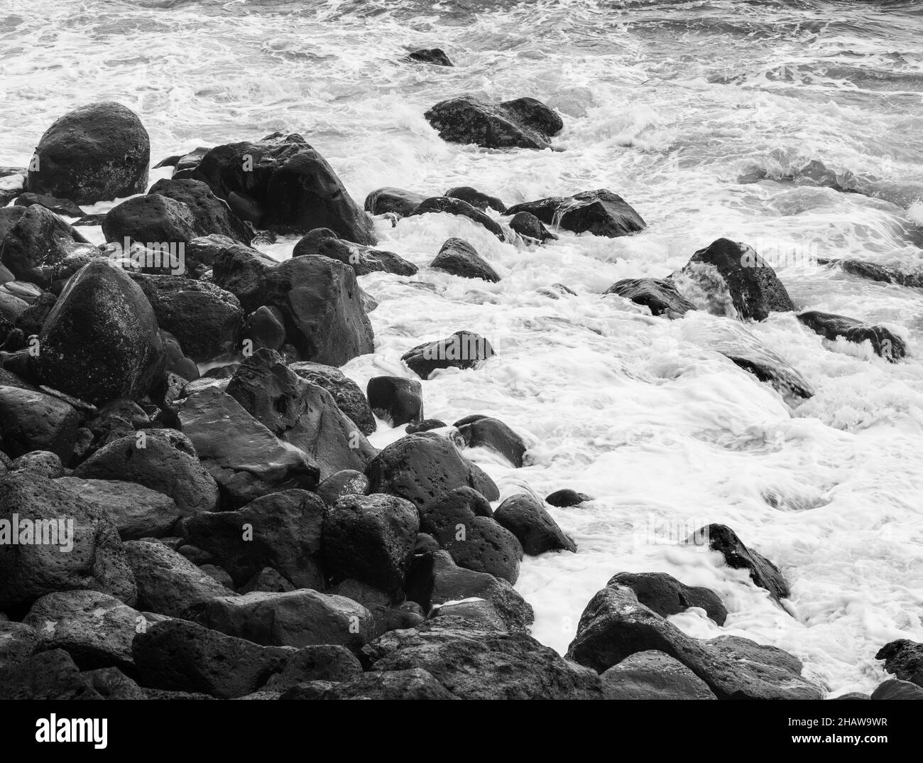 Grandi pietre laviche nere monocromatiche nel surf sulla spiaggia di Rocha da Relva, Isola di Sao Miguel, Azzorre, Portogallo Foto Stock