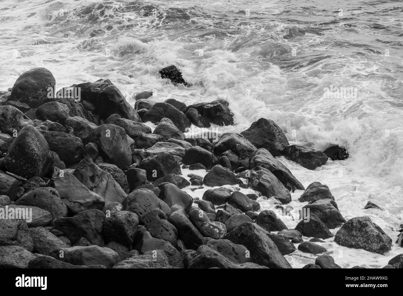 Grandi pietre laviche nere monocromatiche nel surf sulla spiaggia di Rocha da Relva, Isola di Sao Miguel, Azzorre, Portogallo Foto Stock