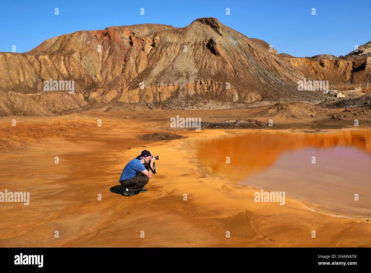 Fotografo di fronte alla montagna con pozzanghere rosse sul sito della miniera, Mazarron, Murcia, Spagna Foto Stock