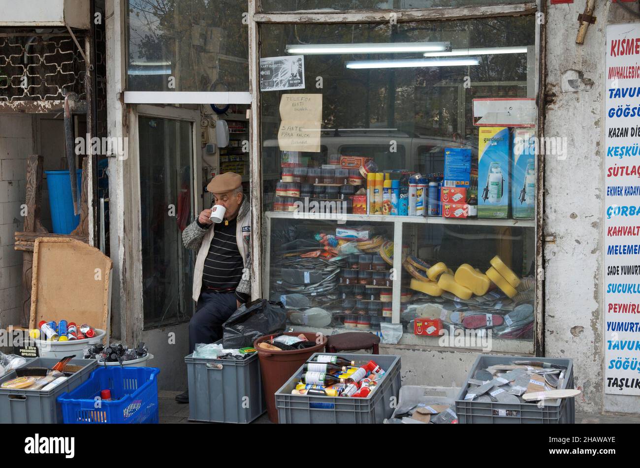Vecchio uomo che beve il tè di fronte al suo negozio con beni di consumo, bevitore di tè di fronte alla porta del negozio, quartiere Eminoenue, Istanbul, Turchia Foto Stock