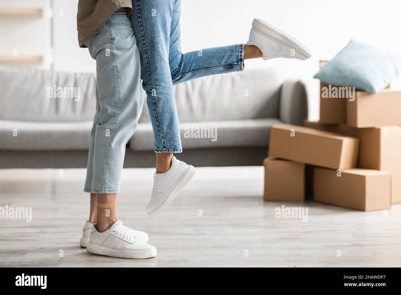 Buon giorno in movimento. Uomo millenario irriconoscibile che abbraccia e solleva la sua ragazza nella propria casa, spazio copia Foto Stock