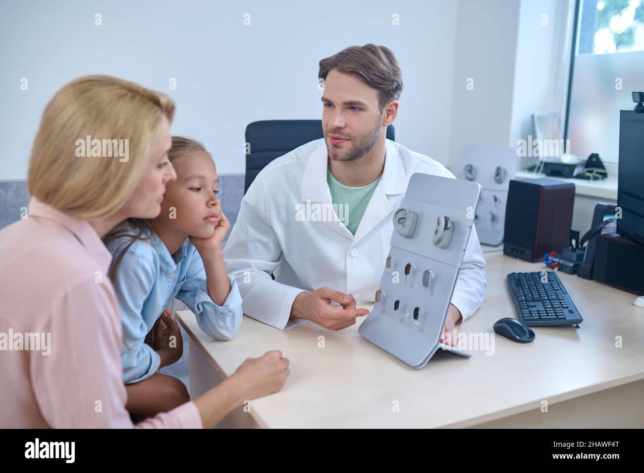 Uomo che mostra apparecchi acustici per agirl e donna Foto Stock
