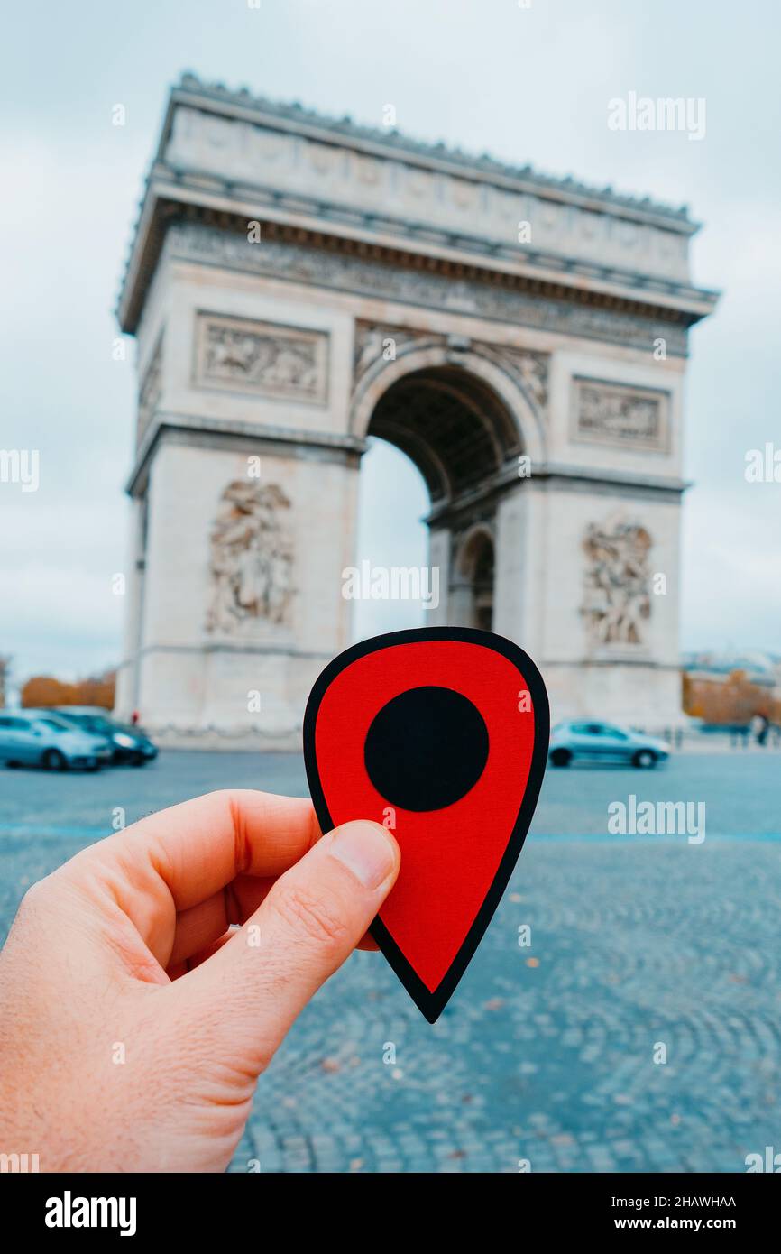 La mano di un giovane caucasico che tiene un marcatore rosso che punta il famoso Arc de Triomph a Parigi, Francia Foto Stock