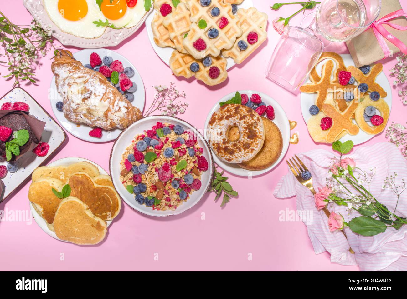 Brunch di San Valentino con vari piatti per colazione e pranzo, waffle, croissant, muffin, ciambelle, frutti di bosco, patatine fritte, panca Foto Stock