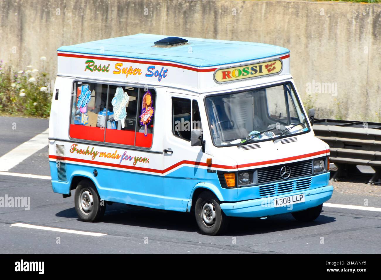 Pubblicità su Blue Mercedes colorato Rossi Ice Cream van aereo lato e vista frontale conducente calcestruzzo parete di ritegno oltre sulla strada autostradale inglese UK Foto Stock