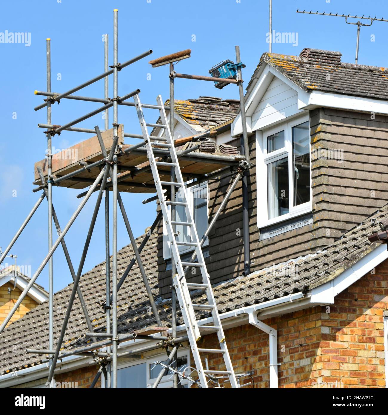 Estensione accesso scala a costruttori ponteggio torre intorno camere dormer per la riparazione di manutenzione tetto e rimontare tegole di colmo tetto semplice per casa Inghilterra UK Foto Stock