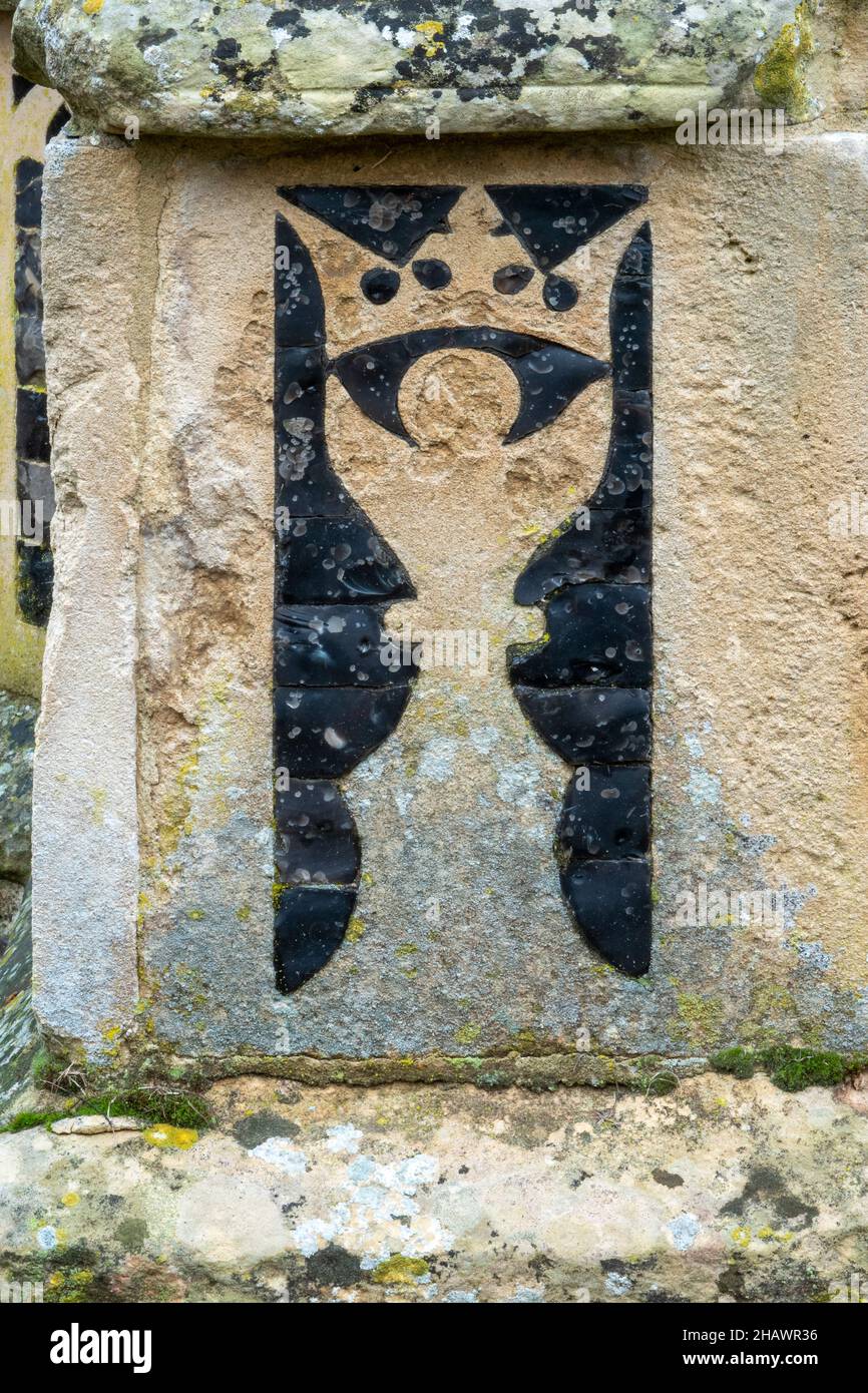 Calice progettato e rappresentato su pietra da un contrasto di pietra fiocchi scuro su un contrafforte che sostiene la chiesa di Santa Maria dell'Assunzione, Ufford Foto Stock