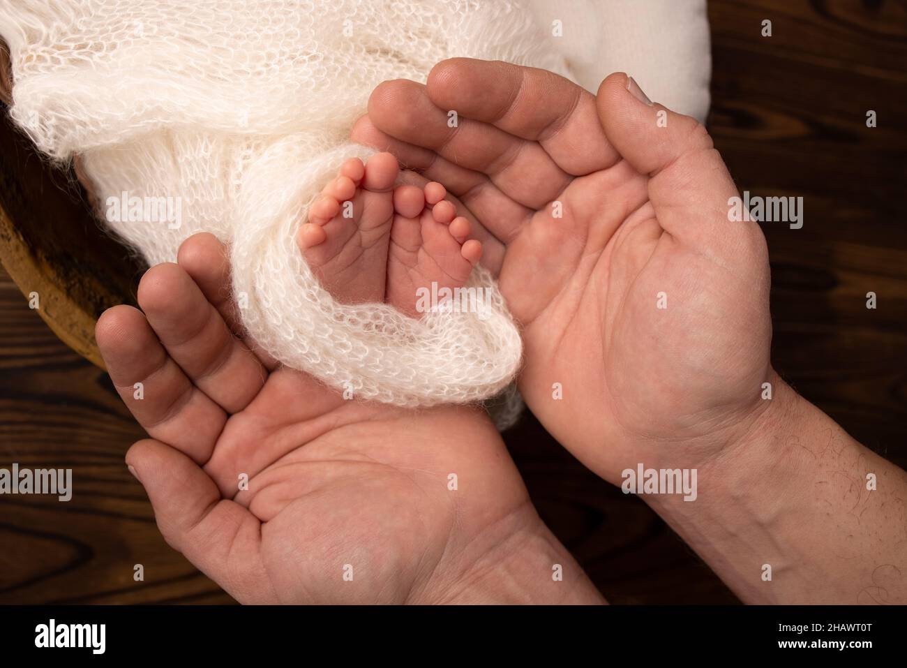 Le palme del padre, la madre stanno tenendo i piedi del neonato Foto Stock