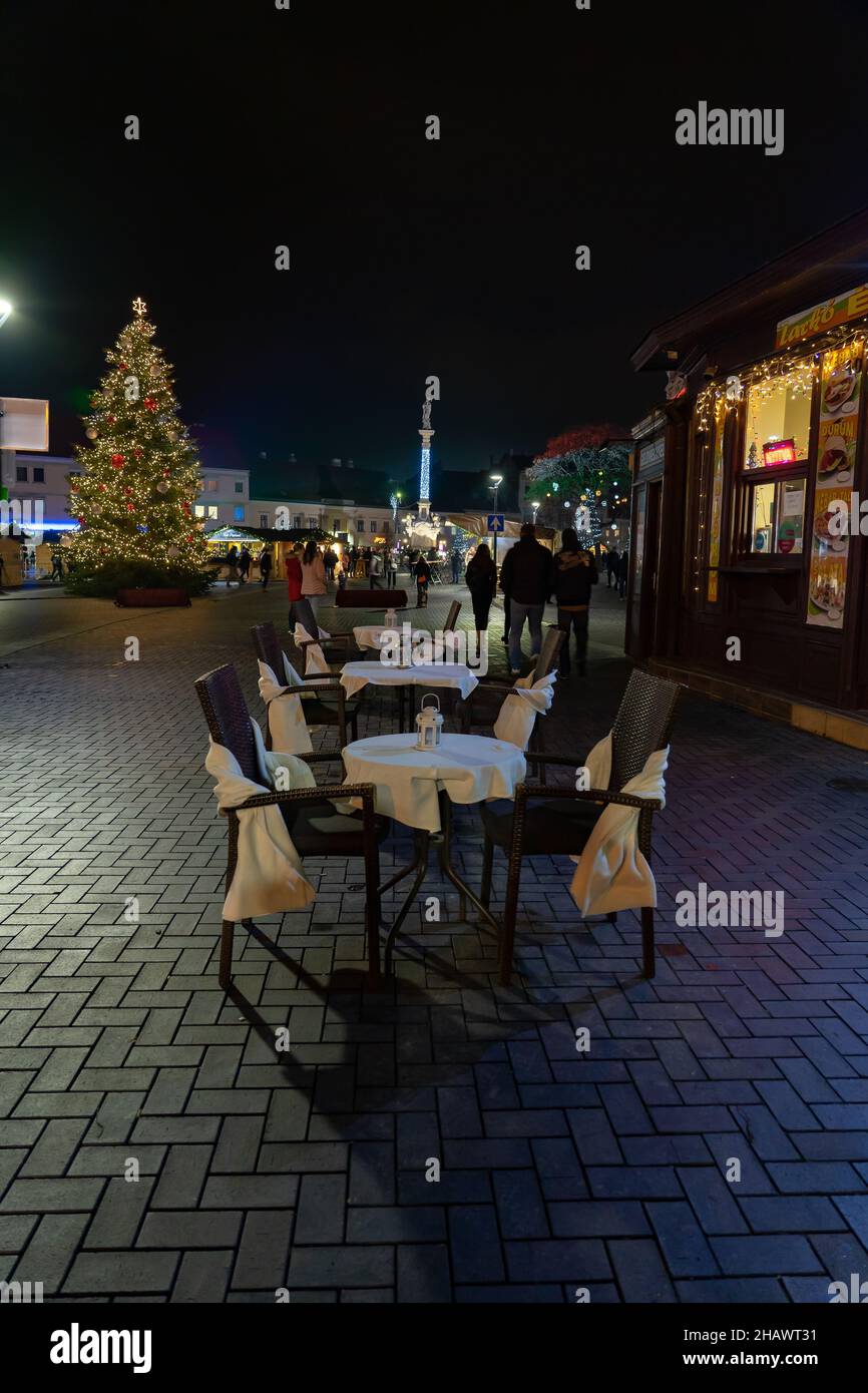 12.14.2021. Sopron, Ungheria: Illuminato Sopron mercatino invernale con tavoli Foto Stock