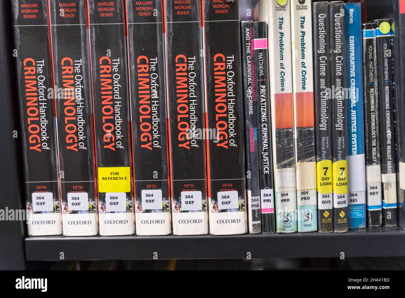 Sei libri del manuale Oxford di Criminologia sullo scaffale accanto ad altri libri in una biblioteca pubblica Inghilterra Regno Unito Foto Stock