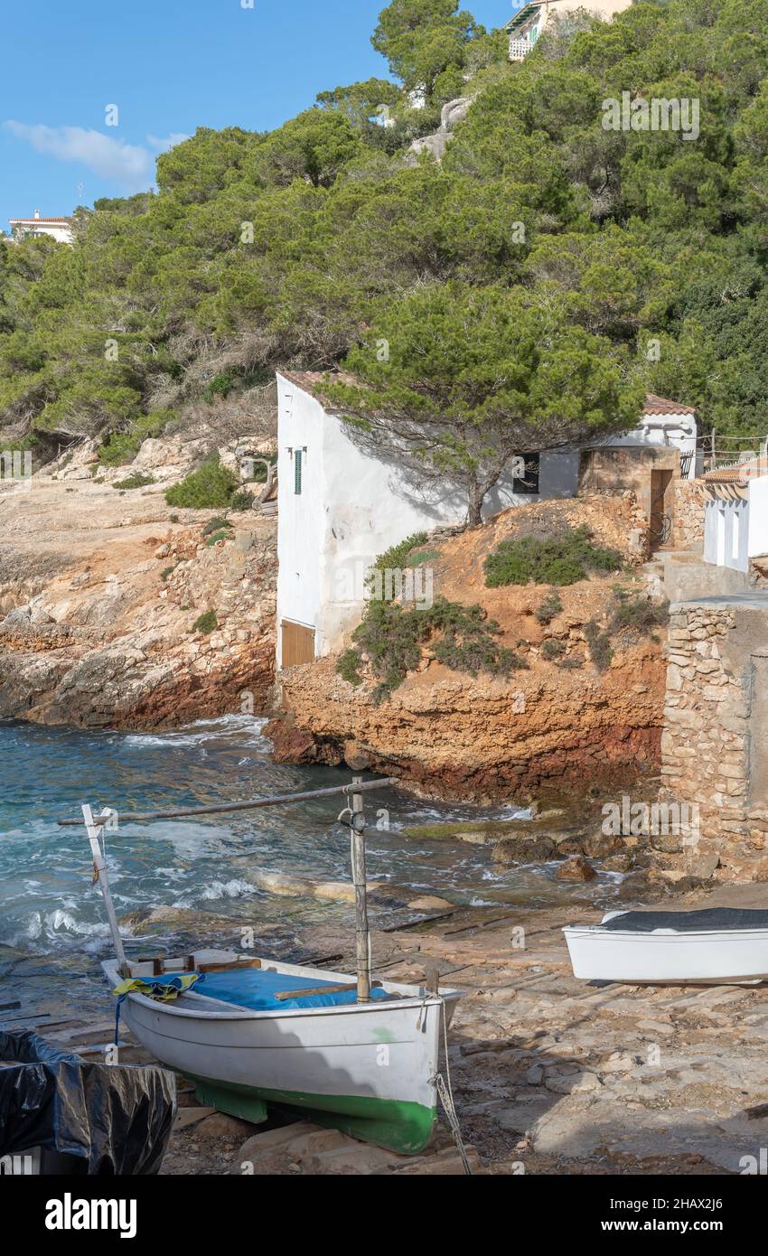 Paesaggio della costa rocciosa dell'isola di Maiorca, con un villaggio di pescatori costiero, una giornata invernale nuvolosa e soleggiata. Baia di S'Almonia Foto Stock