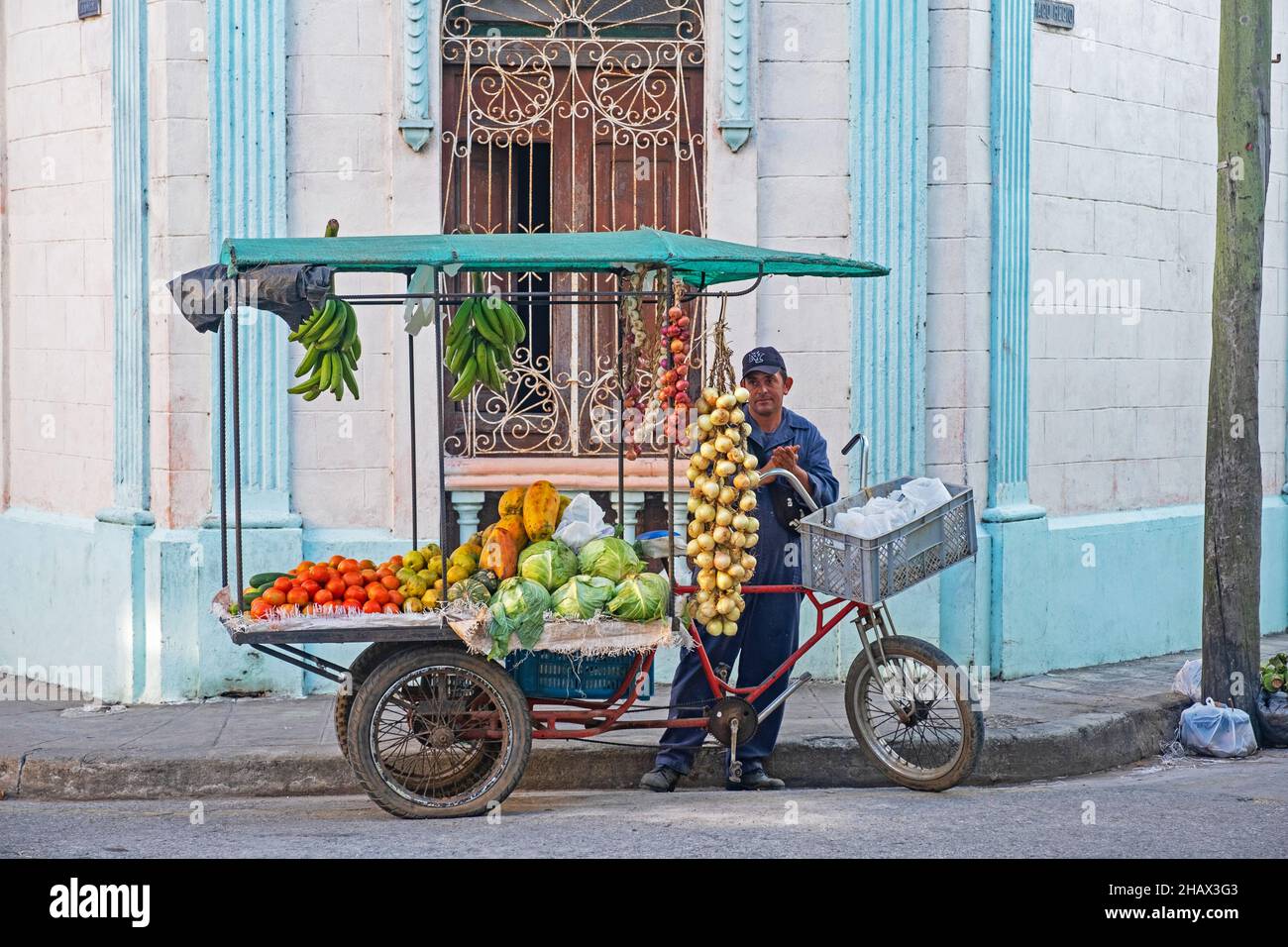 Venditore di strada cubano che vende frutta e verdura da mobile cibo stand su triciclo nella città Camagüey sull'isola Cuba, Caraibi Foto Stock