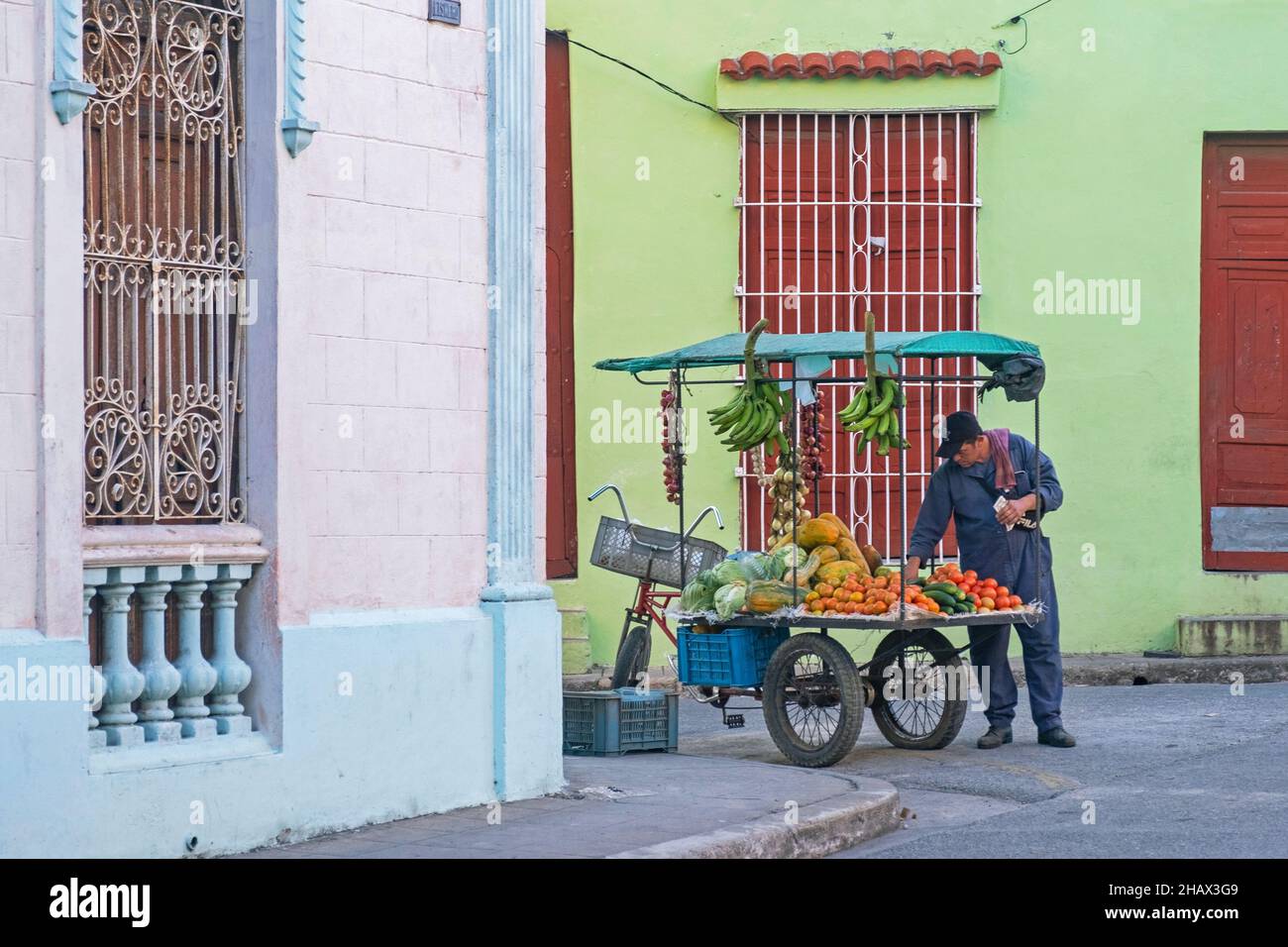 Venditore di strada cubano che vende frutta e verdura da mobile cibo stand su triciclo nella città Camagüey sull'isola Cuba, Caraibi Foto Stock