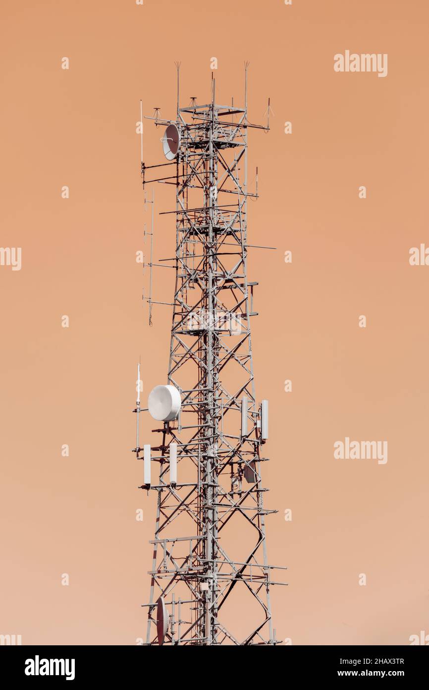 Fotografia di una grande torre di telecomunicazioni in acciaio su sfondo di cielo arancione Foto Stock