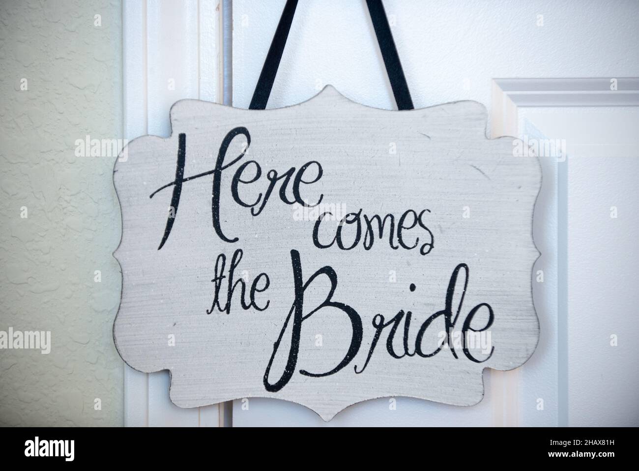 'Ecco la sposa' segno su legno bianco con lettere nere Foto Stock