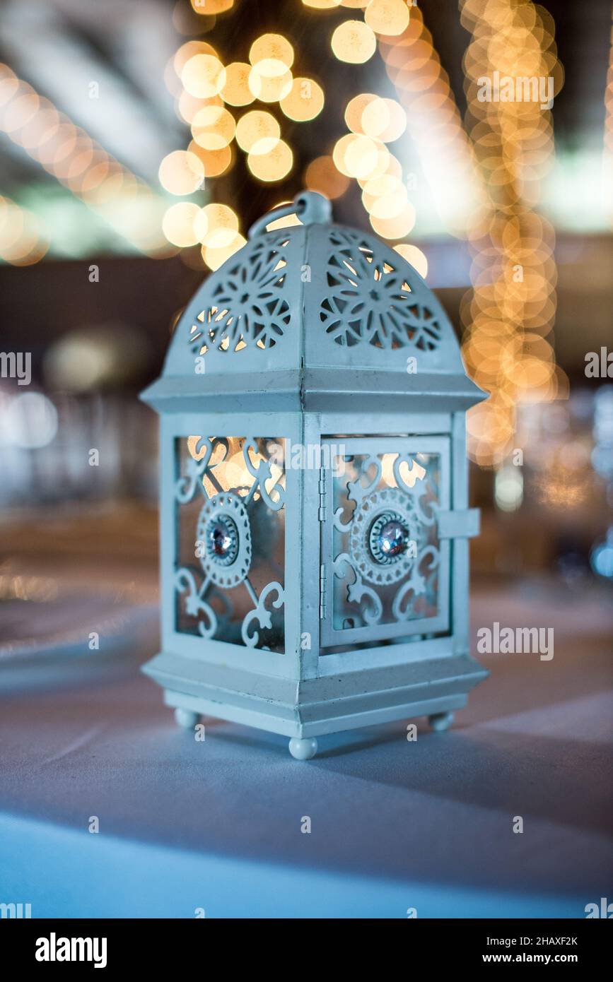 Centrotavola porta lanterna a candela blu ornata su tavolo con bokeh Foto Stock