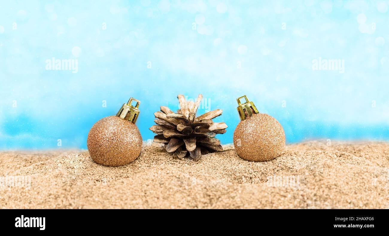 Palle lucenti con cono di pino sulla spiaggia. Concetto per Natale, Capodanno, Beach Party. Spazio di copia Foto Stock