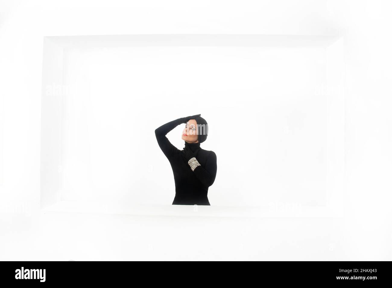 donna elegante realizzata e vestita in nero con turbante e guanti su sfondo bianco con spazio copia Foto Stock
