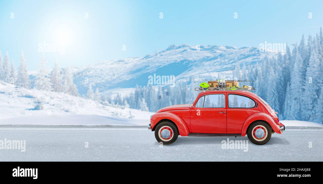 Auto rossa con attrezzatura da sci sul tetto sulla strada per il concetto di stazione sciistica. Montagna sullo sfondo Foto Stock