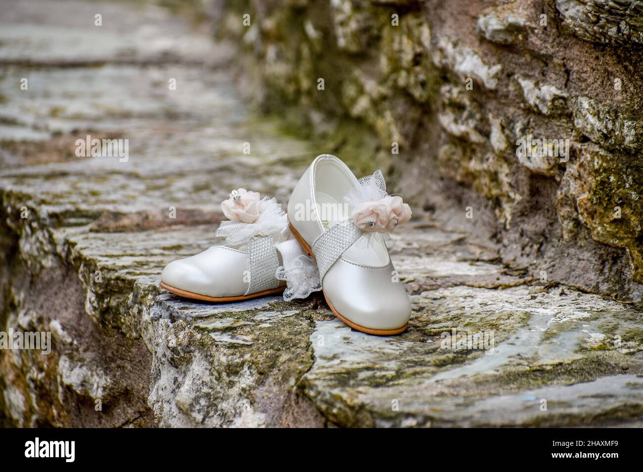 Primo piano di scarpe da bambino perla ragazze spagnole, occasione di  battesimo su una superficie rocciosa Foto stock - Alamy