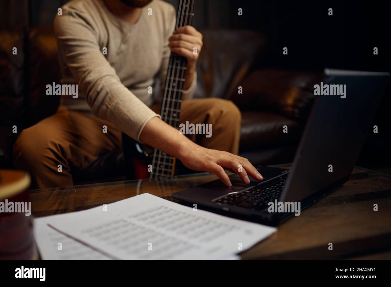 Giovane uomo che impara a suonare la chitarra attraverso internet Foto Stock