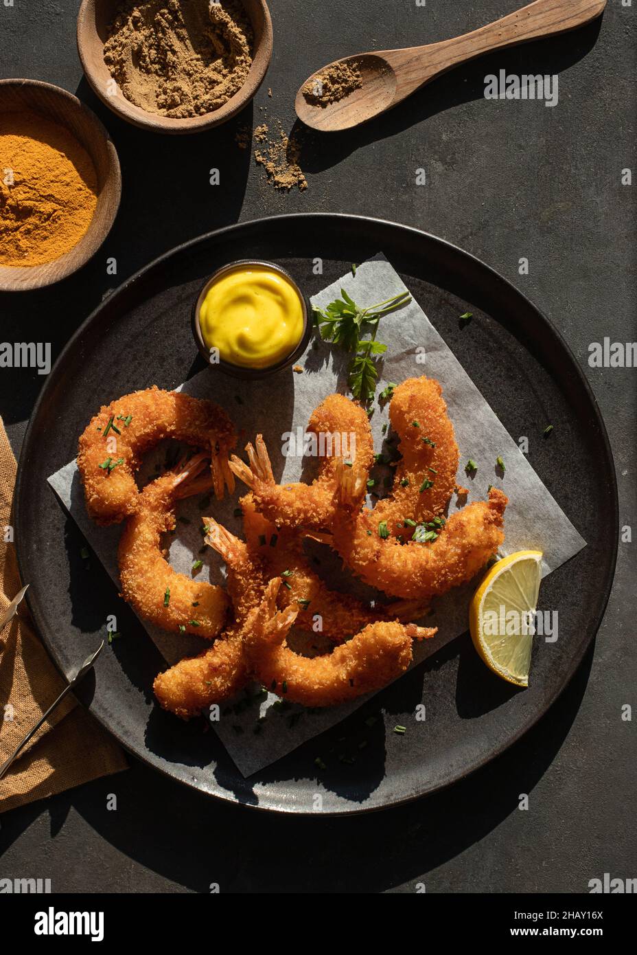Dall'alto ancora vita con piatto di gamberi in pastella di limone e senape con due ciotole di spezie curcuma e curry Foto Stock