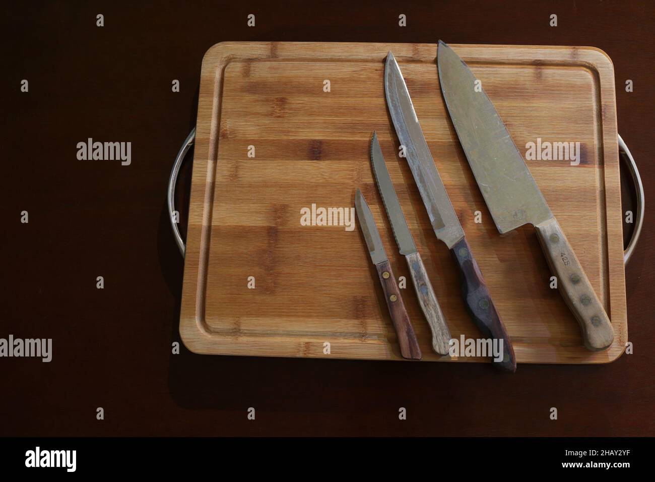 Coltelli di diverse dimensioni disposti in fila su un tagliere ordinato dal più piccolo al più grande Foto Stock