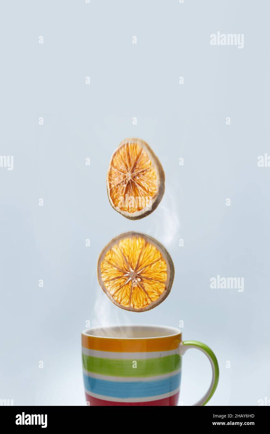 Goiânia, Goias, Brasile – 15 dicembre 2021: Una tazza colorata con tè caldo e due fette d'arancia che cadono. Foto Stock