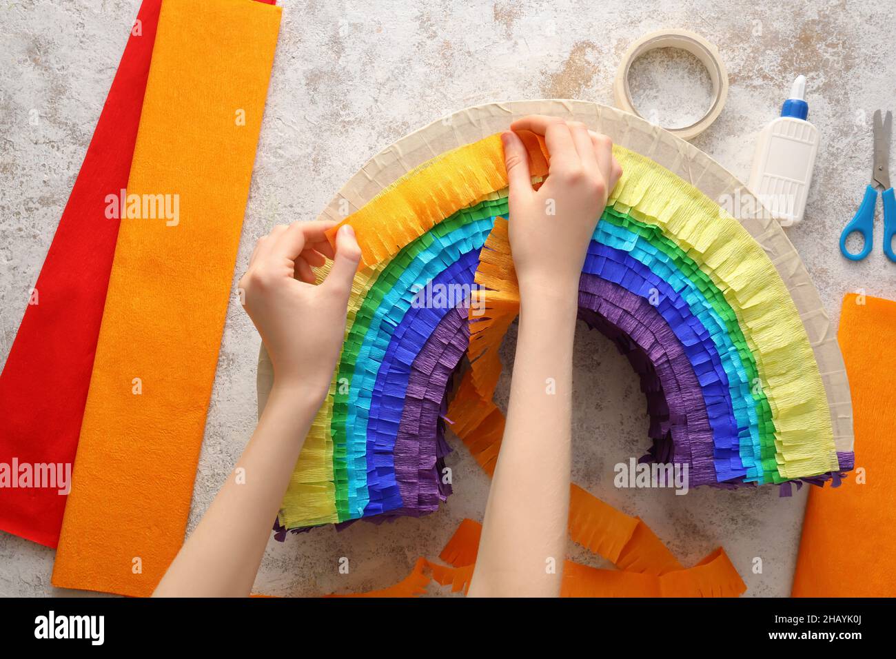 Donna che fa pinata messicana a forma di arcobaleno su sfondo grunge Foto Stock