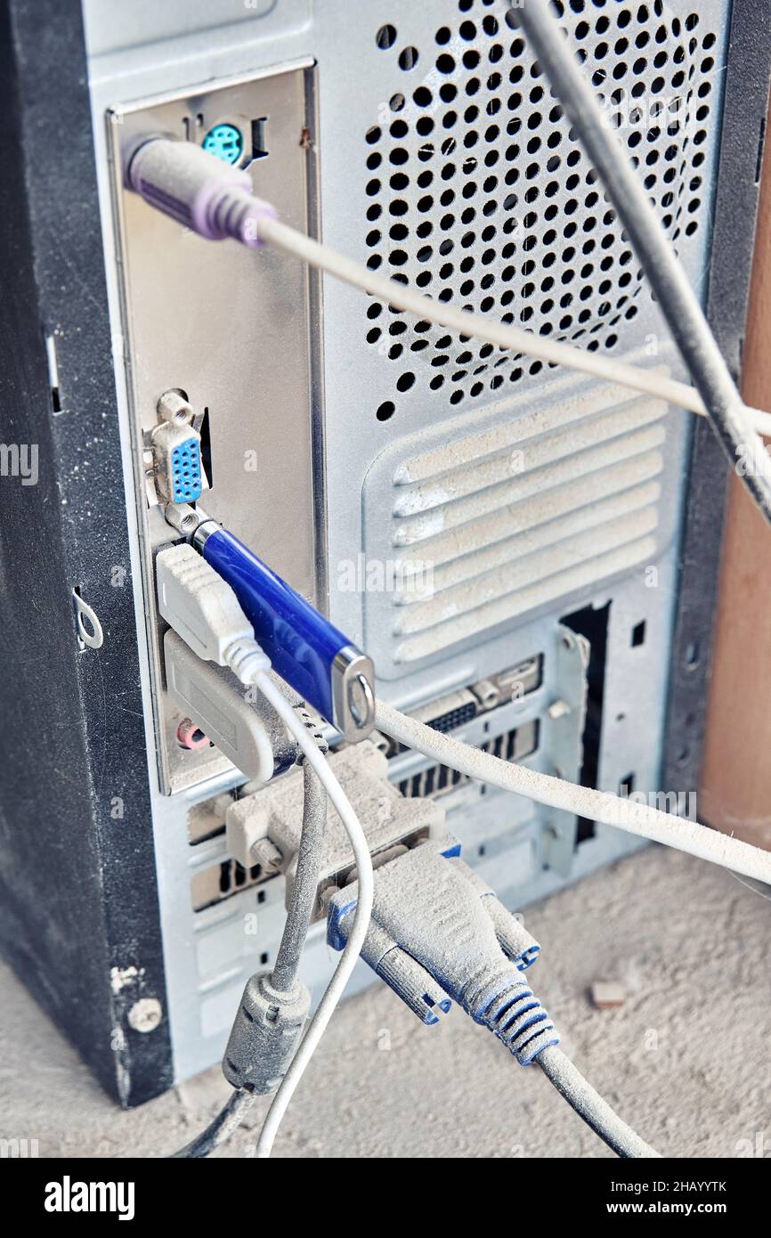 La vista posteriore del vecchio computer sporco è coperta da uno spesso strato di polvere, in piedi sul pavimento dell'officina Foto Stock