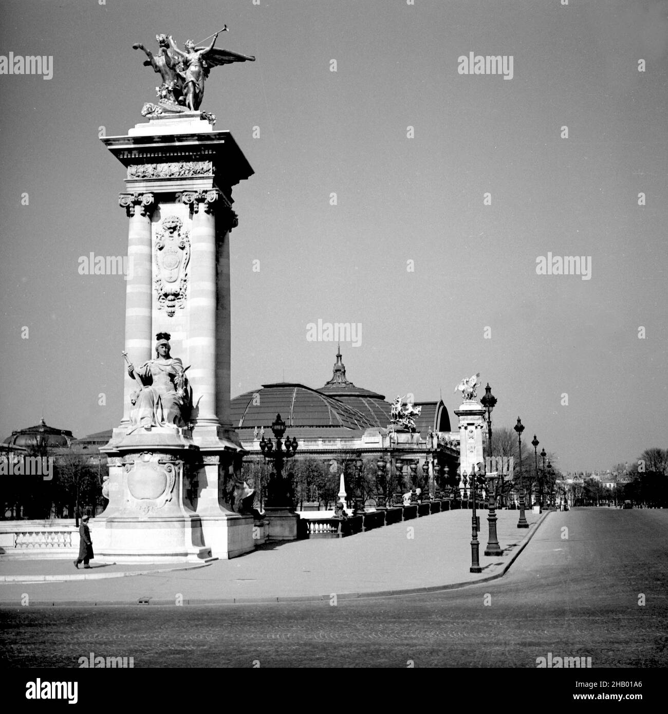 Paris Pont Alexandre III con la Fame dell'industria (Renommée de l'Industrie) scultura in bronzo, 1945. La macchina fotografica è puntata dalla riva sinistra della Senna al famoso ponte ornato del fiume con uno dei quattro sucoli in muratura che domina l'immagine a sinistra. L'immagine intagliata in muratura è di Luigi XIV. Non ci sono persone sulla passerella e non ci sono veicoli sulla strada del ponte. Il Grand Palais è visto sullo sfondo dell'immagine. Appena sei mesi prima che questa foto fosse scattata, quel palazzo servì come sede della SS tedesca a Parigi. Foto Stock