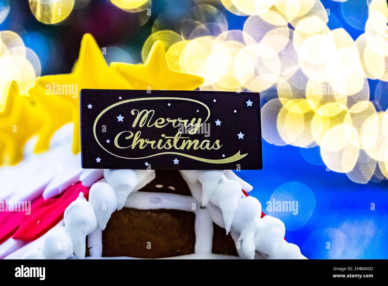 Casa del pane di zenzero con saluto di Natale allegro e bokeh sfondo. Foto Stock