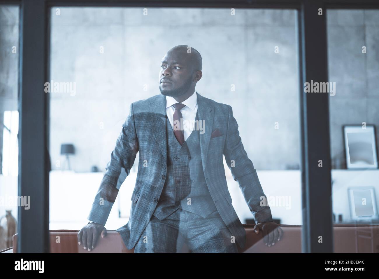 Uomo d'affari di successo, Main Investor guarda di lato e si leva con sicurezza dietro il muro di vetro nel suo elegante ufficio . Primo piano. Foto di alta qualità Foto Stock