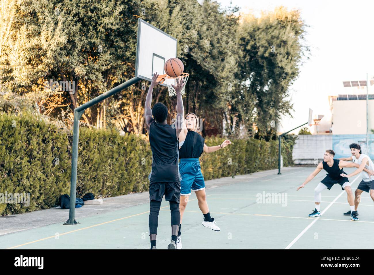 Quattro amici che giocano a basket in un campo pubblico all'aperto Foto Stock