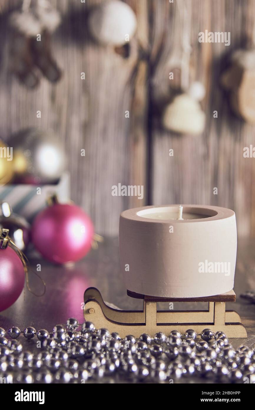 Candela di cera di soia fatta a mano in un candeliere di argilla sullo sfondo di un arredamento di Capodanno. Foto Stock