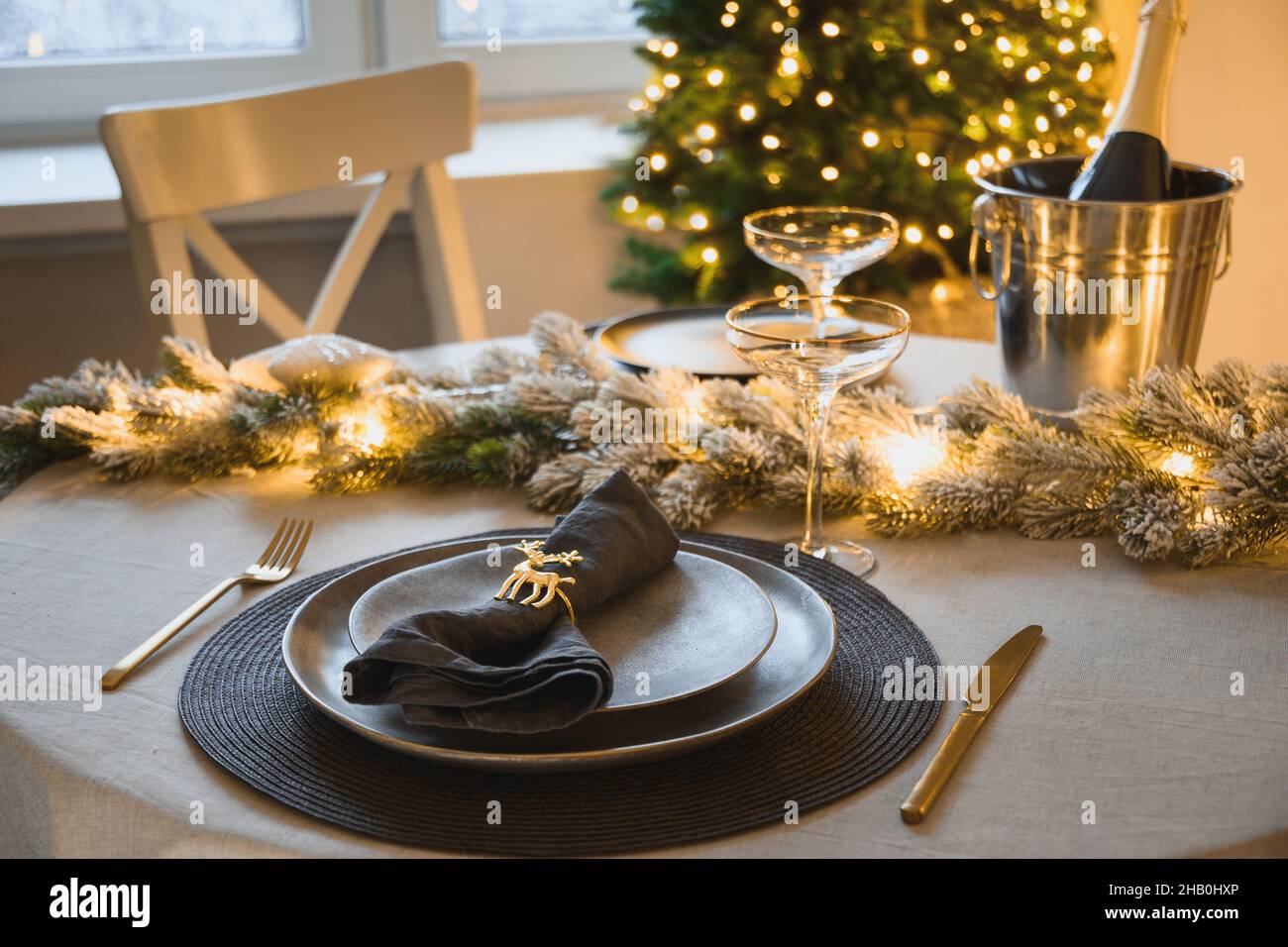 Natale elegante tavolo decorato ghirlanda d'oro, piatto grigio con anello tovagliolo. Cena per famiglie a casa. Primo piano. Foto Stock