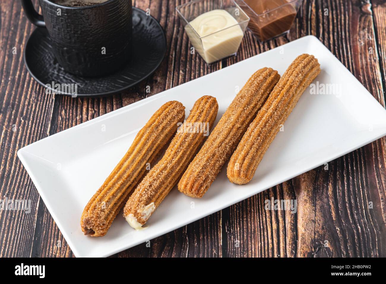 Churros caldi con salsa di cioccolato su tavola di legno. Foto Stock