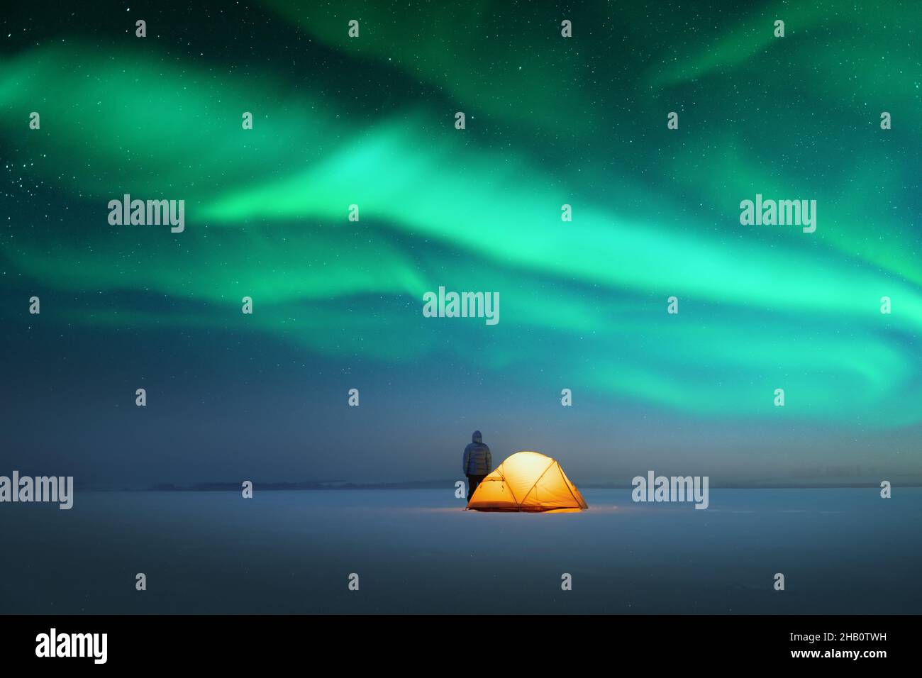 Turista vicino giallo tenda illuminata dall'interno contro lo sfondo di incredibile cielo stellato con Aurora borealis. Panorama notturno incredibile. Aurora boreale in campo invernale Foto Stock