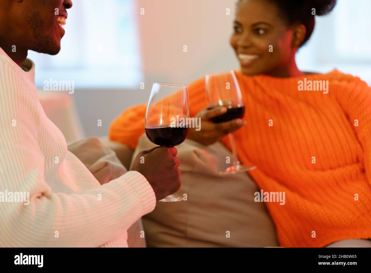 Data a casa. Giovani coppie afro-americane parlano sedersi sul divano e bere vino insieme nel fine settimana Foto Stock
