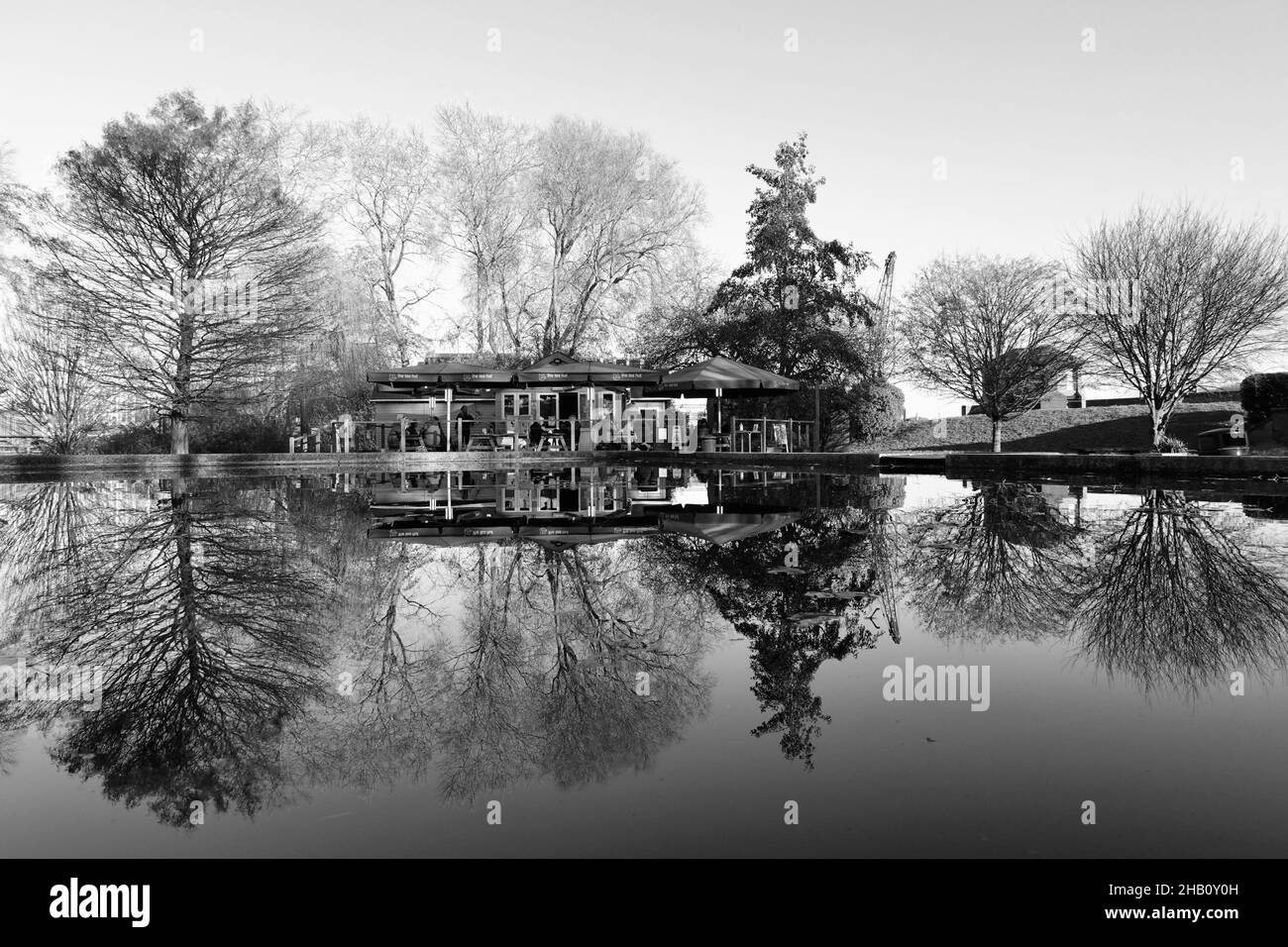 Woodbridge, Suffolk, UK - 16 dicembre 2021: The Tea Hut, un caffè accanto al fiume Deben. L'edificio si riflette nel laghetto in barca in una luminosa mattinata invernale. Immagine monocromatica. Foto Stock