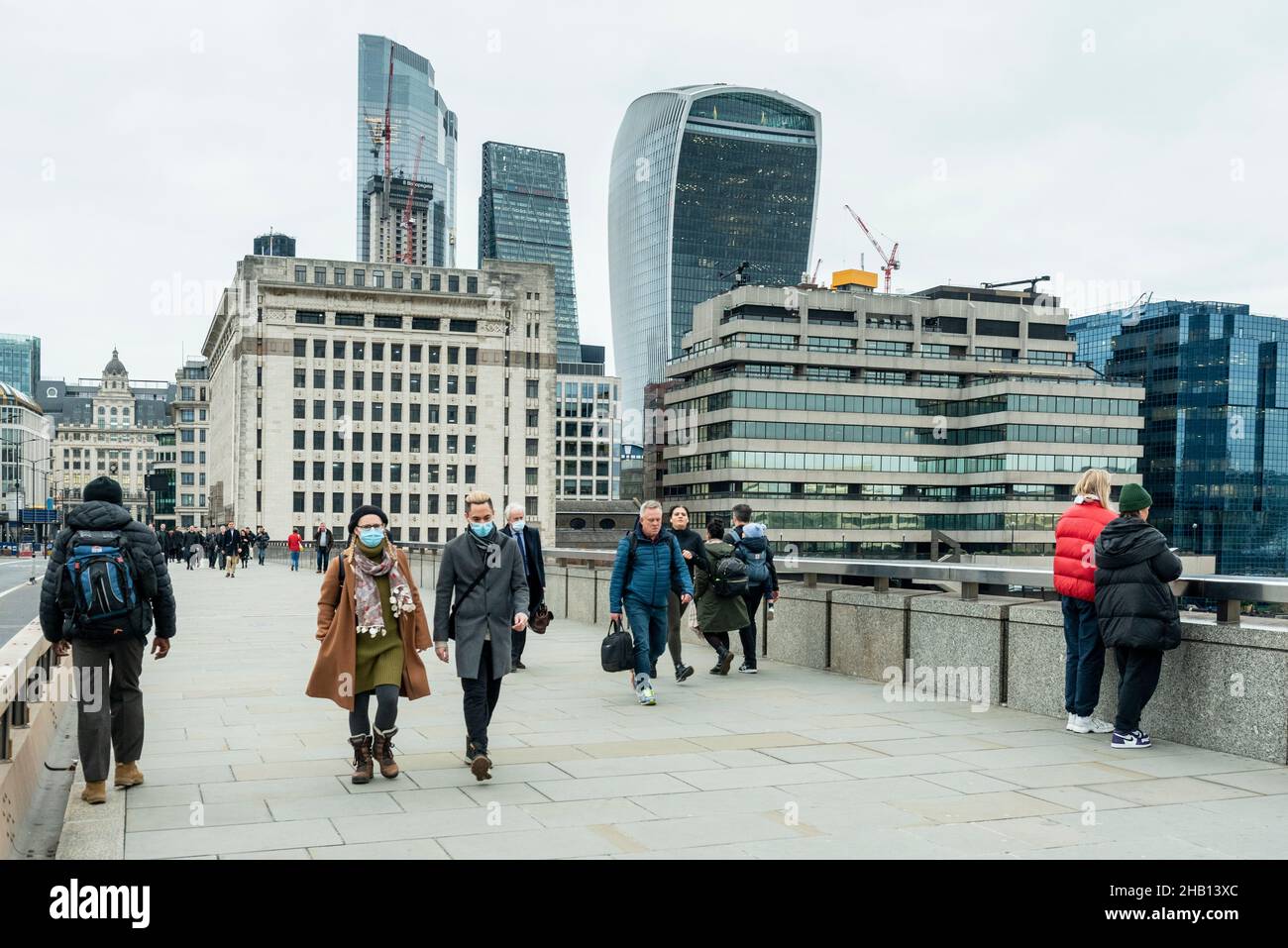 Londra, Regno Unito. 16 dicembre 2021. La gente attraversa il London Bridge con i grattacieli della City of London in lontananza. La Banca d'Inghilterra ha annunciato che ha aumentato il tasso d'interesse dal 0,1% al 0,25% in risposta all'aumento dell'inflazione al 5,1% e hanno già previsto che il tasso d'inflazione salirà al 6% il prossimo anno. Credit: Stephen Chung / Alamy Live News Foto Stock
