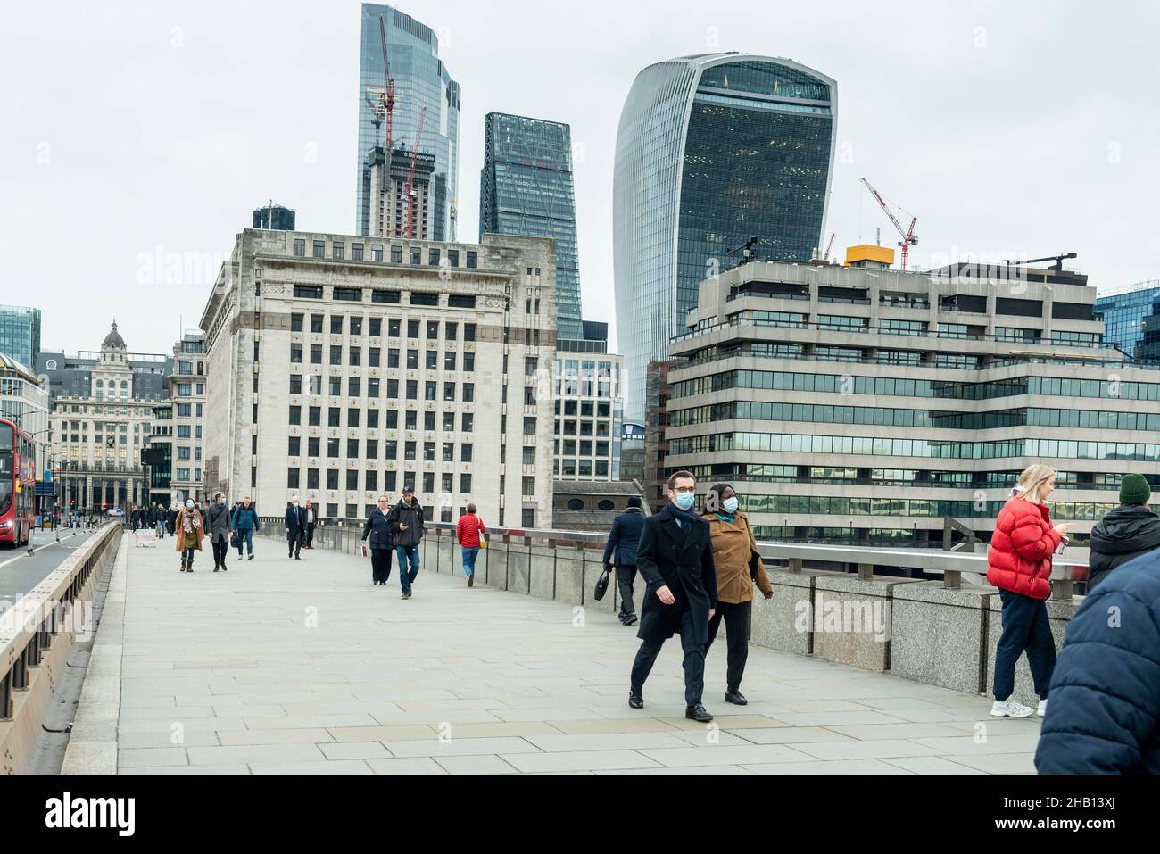 Londra, Regno Unito. 16 dicembre 2021. La gente attraversa il London Bridge con i grattacieli della City of London in lontananza. La Banca d'Inghilterra ha annunciato che ha aumentato il tasso d'interesse dal 0,1% al 0,25% in risposta all'aumento dell'inflazione al 5,1% e hanno già previsto che il tasso d'inflazione salirà al 6% il prossimo anno. Credit: Stephen Chung / Alamy Live News Foto Stock
