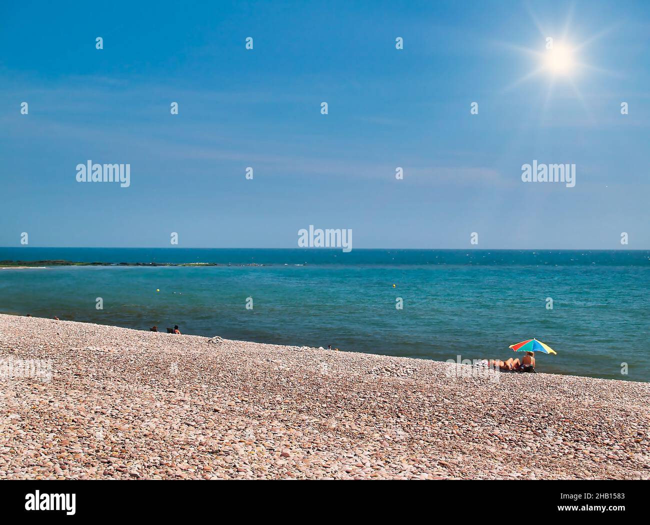 Il sole estivo si bagna sulla spiaggia di pietra di Budleigh Salterton nel Devon orientale, Inghilterra sudoccidentale Foto Stock