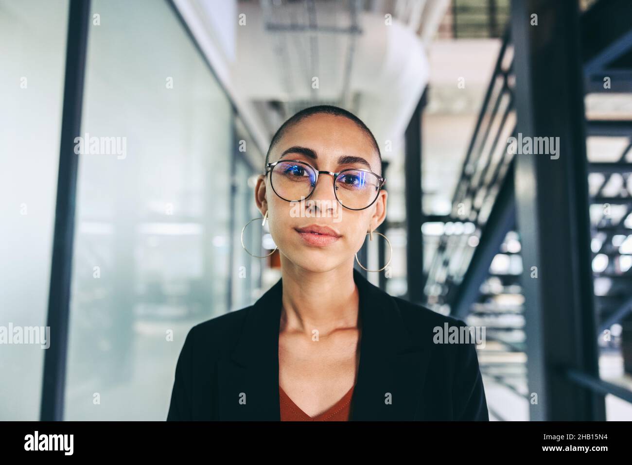 Giovane donna d'affari che guarda la macchina fotografica. Giovane donna d'affari fiduciosa in piedi in un ambiente di lavoro moderno in un abbigliamento casual d'affari. Business wom intelligente Foto Stock