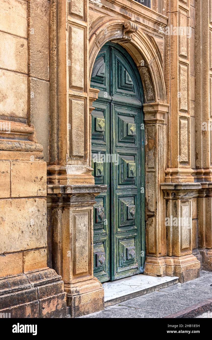 Grande porta di legno verde e facciata in pietra all'ingresso della vecchia chiesa storica di Pelourinho in Salvador Foto Stock