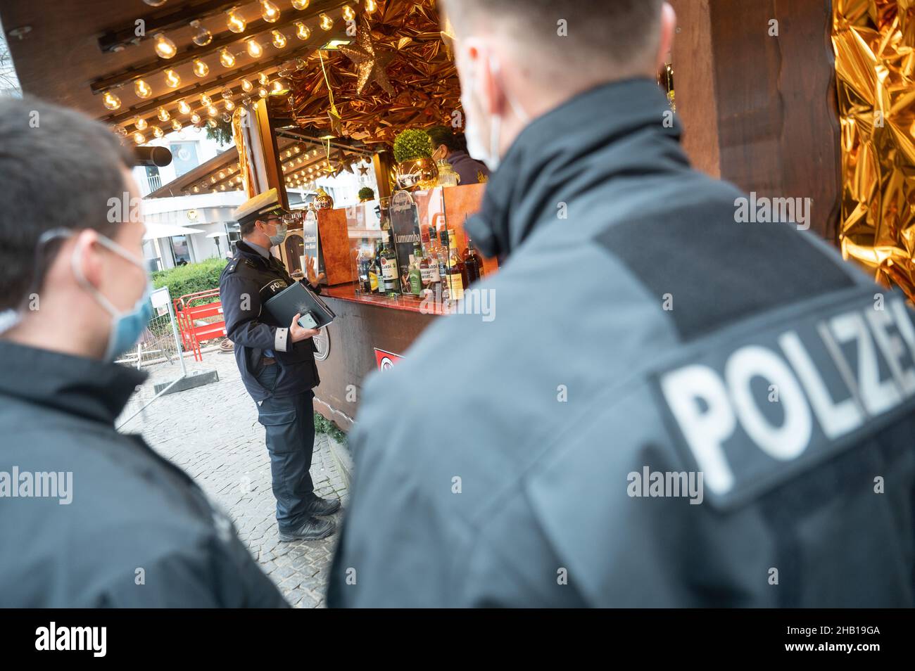 Magonza, Germania. 16th Dic 2021. Un funzionario di polizia parla con un operatore di stallo durante un giorno di controllo di conformità a livello nazionale per la pandemia di coronavirus al mercato di Natale. Credit: Sebastian Gollnow/dpa/Alamy Live News Foto Stock