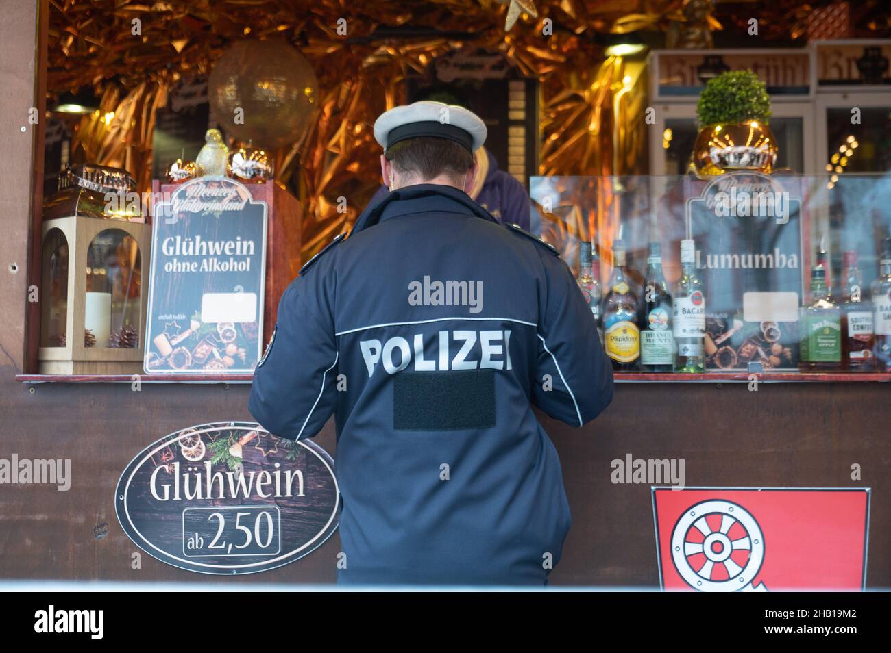 Magonza, Germania. 16th Dic 2021. Un funzionario di polizia parla con un operatore di stallo durante un giorno di controllo di conformità a livello nazionale per la pandemia di coronavirus al mercato di Natale. Credit: Sebastian Gollnow/dpa/Alamy Live News Foto Stock