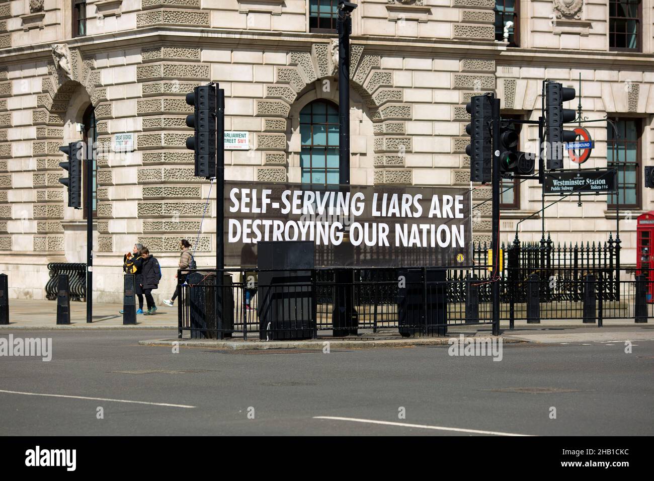 Un vessillo contro l'attuale governo conservatore è messo in su vicino alle Camere del Parlamento a Westminster, centro di Londra. Foto Stock